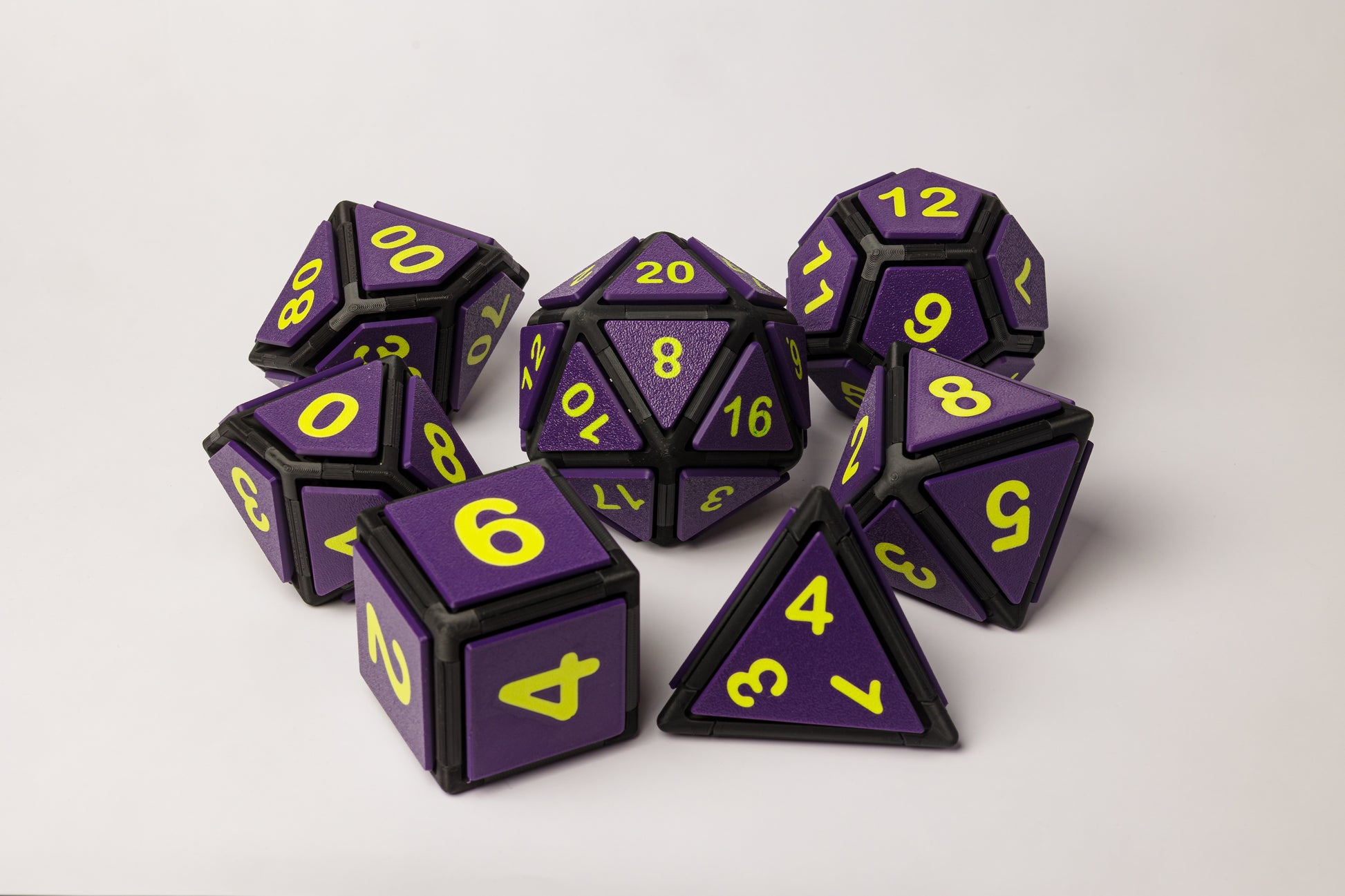 Set of purple and black polyhedral dice with neon green numbers on a white background